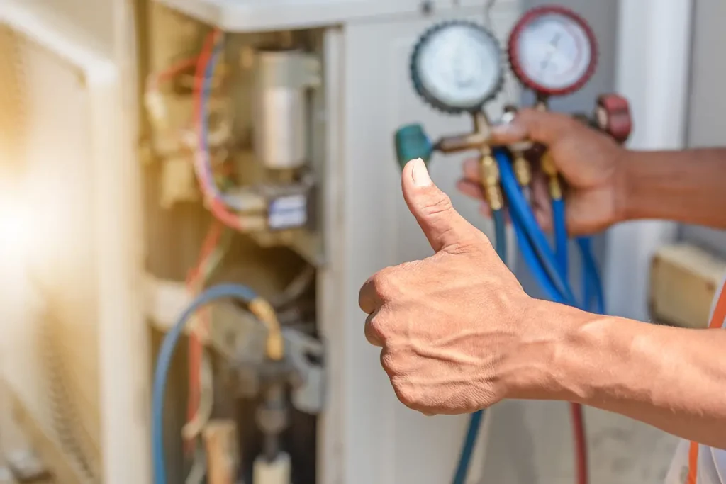 repair technician giving a thumbs up while testing an air conditioning unit